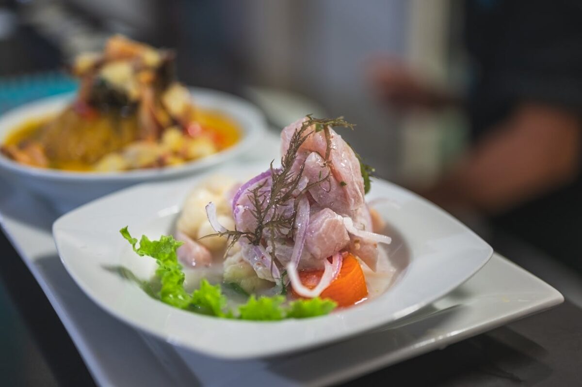 A vibrant dish of ceviche served on a white plate with colorful garnishes, offering fresh flavors.